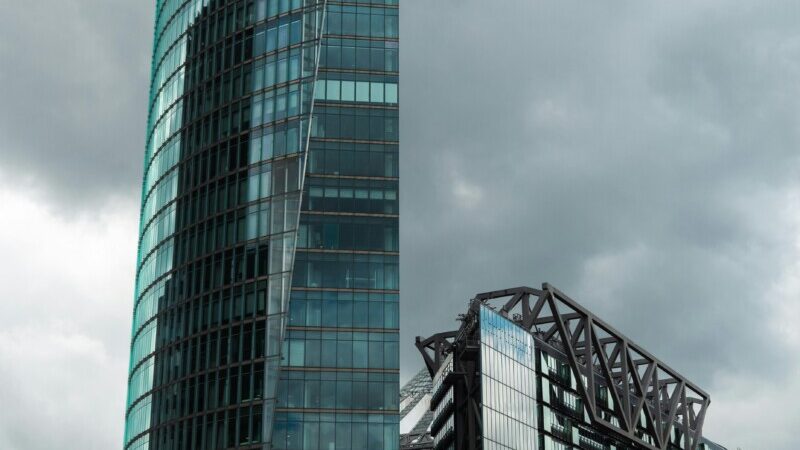Skyscraper and train station at Potsdamer Platz, Berlin, under cloudy skies.